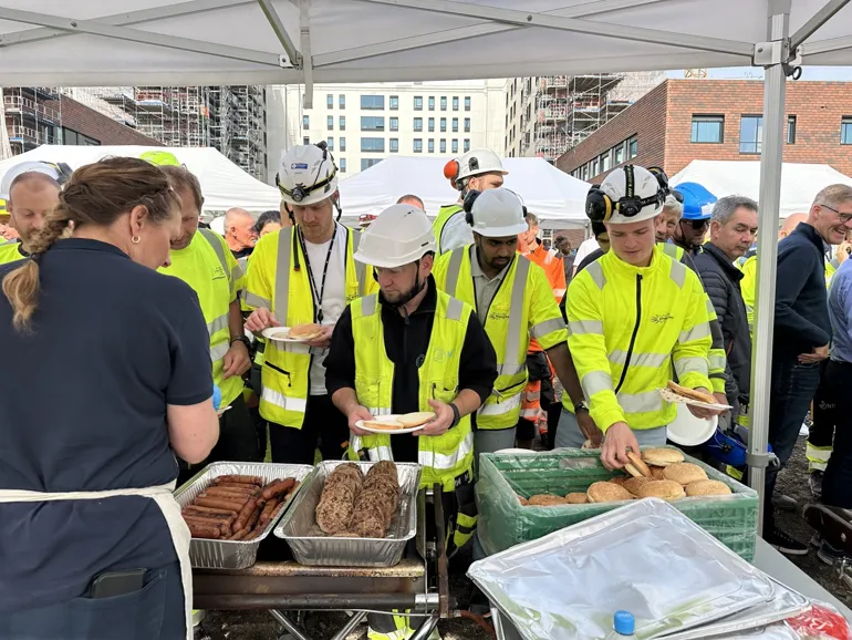 En gruppe mennesker i sikkerhetsvester som står rundt et bord med mat